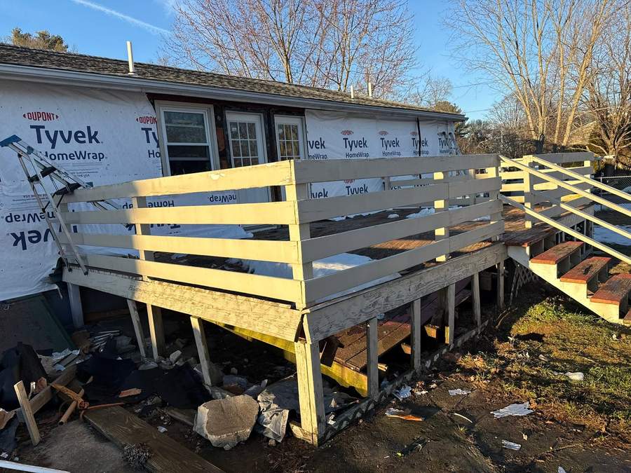 New deck framing and posts going in against a house wrapped in DuPont Tyvek during a South Shore rebuild by CB Builders Corp.