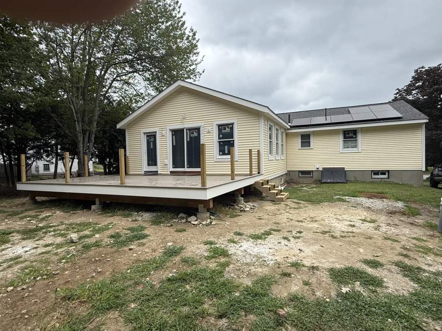 Completed home addition with matching vinyl siding, windows, trim, and an adjoining platform deck